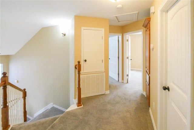 corridor featuring baseboards, carpet flooring, an upstairs landing, and attic access