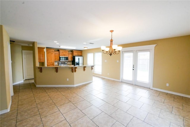 kitchen with decorative light fixtures, an inviting chandelier, appliances with stainless steel finishes, a peninsula, and a kitchen breakfast bar