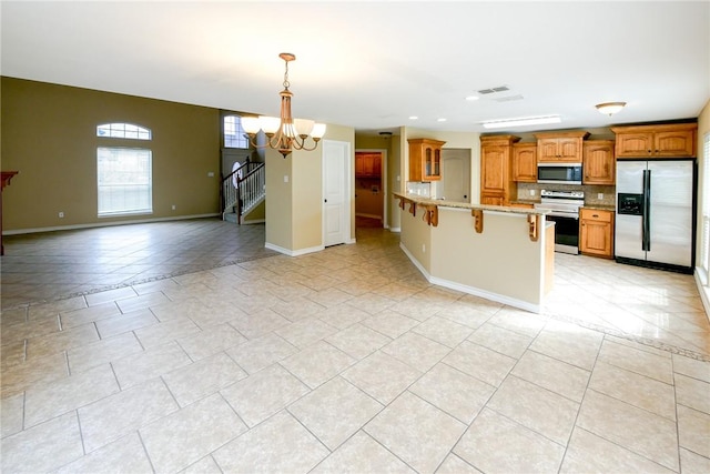 kitchen featuring tasteful backsplash, appliances with stainless steel finishes, a breakfast bar, open floor plan, and a notable chandelier