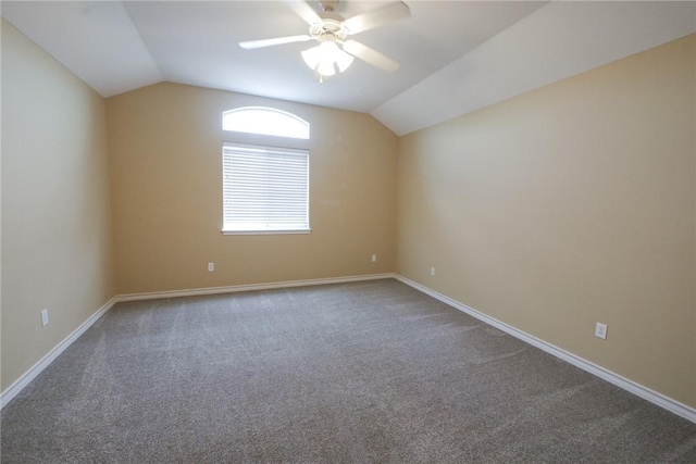 carpeted spare room with vaulted ceiling, a ceiling fan, and baseboards