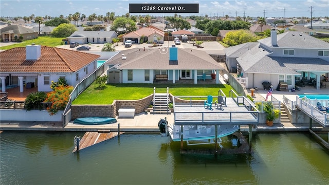 view of dock featuring a patio area, a water view, and a yard