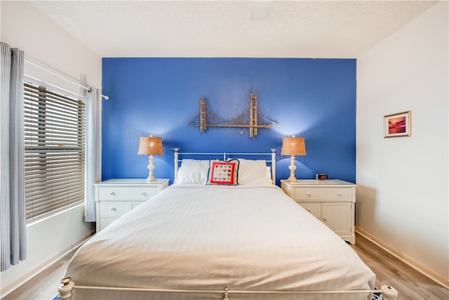 bedroom featuring a textured ceiling, light wood-type flooring, and ceiling fan