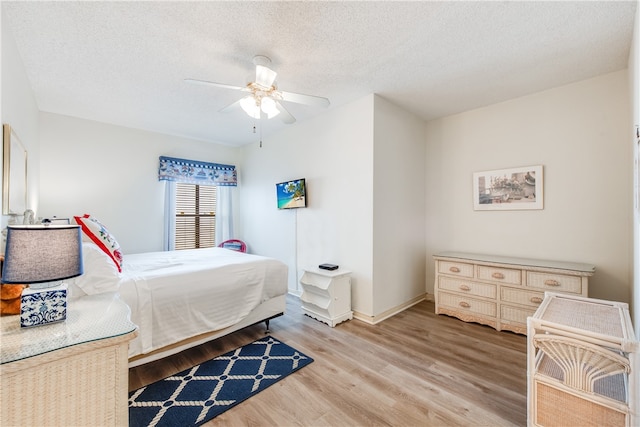 bedroom with a textured ceiling, light hardwood / wood-style floors, and ceiling fan