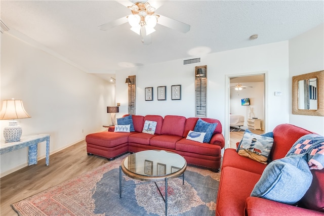 living room featuring ceiling fan, a textured ceiling, and light hardwood / wood-style floors