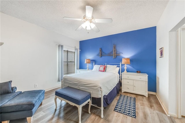 bedroom with a textured ceiling, wood finished floors, a ceiling fan, and baseboards