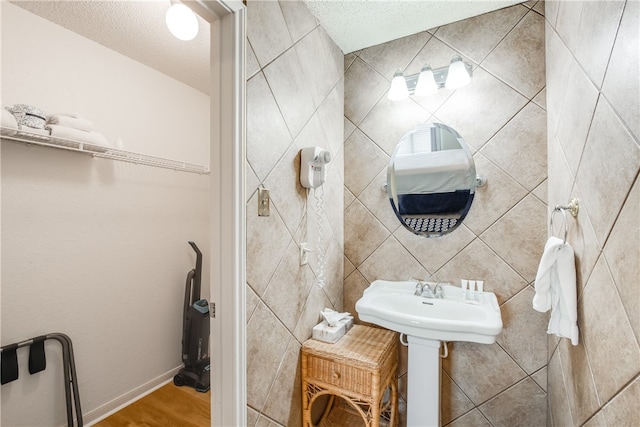 bathroom featuring tile walls, a textured ceiling, and wood-type flooring