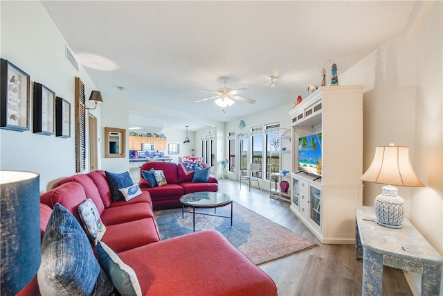 living room with a textured ceiling, hardwood / wood-style flooring, and ceiling fan