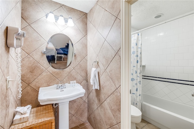 bathroom with tile patterned floors, toilet, tile walls, a textured ceiling, and shower / bathtub combination with curtain