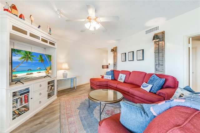 living room with light hardwood / wood-style floors, ceiling fan, and a textured ceiling