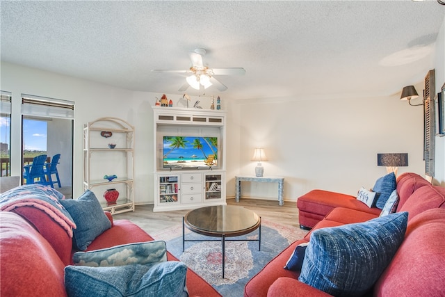 living room featuring a textured ceiling, light wood-type flooring, and ceiling fan