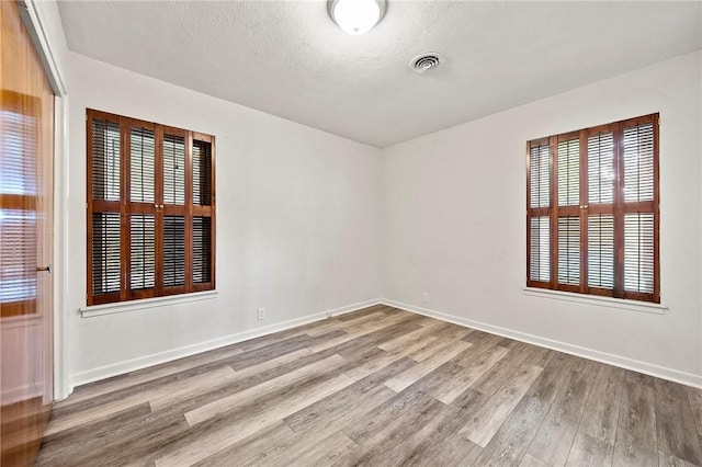 4414 Driftwood Pl, Corpus Christi, TX 78411 - unfurnished room with wood finished floors, healthy amount of natural light, baseboards, and a textured ceiling