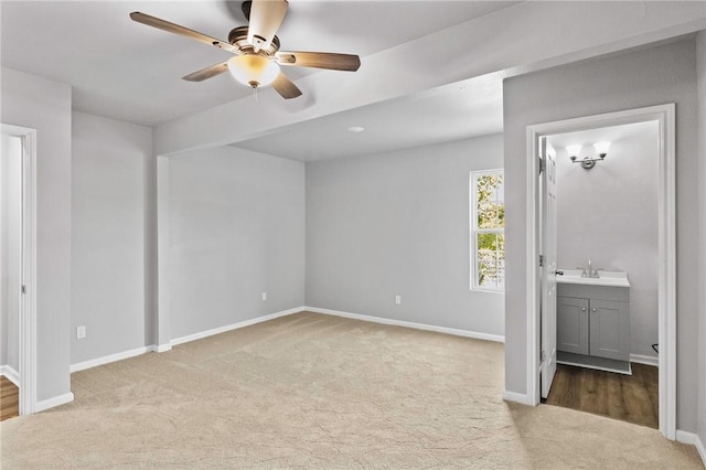 unfurnished bedroom with ceiling fan, sink, light carpet, and connected bathroom