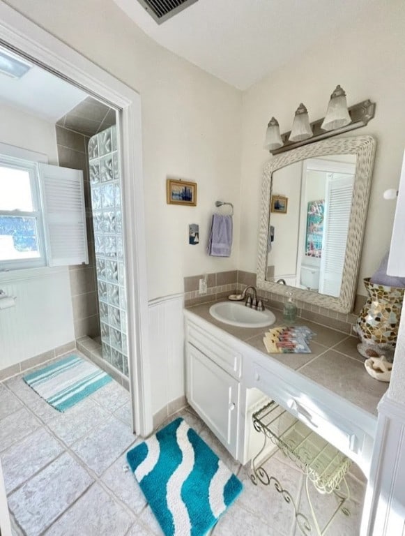 1878 Bay Shore Dr, Rockport, TX 78382 - bathroom featuring tile patterned flooring, visible vents, a wainscoted wall, a tile shower, and vanity