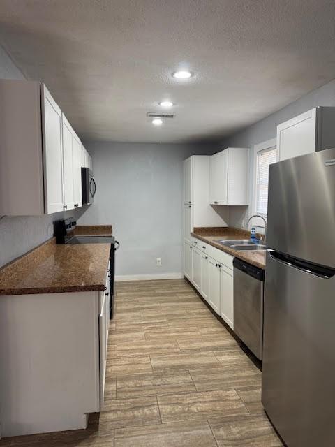 kitchen with stainless steel appliances, white cabinets, and sink