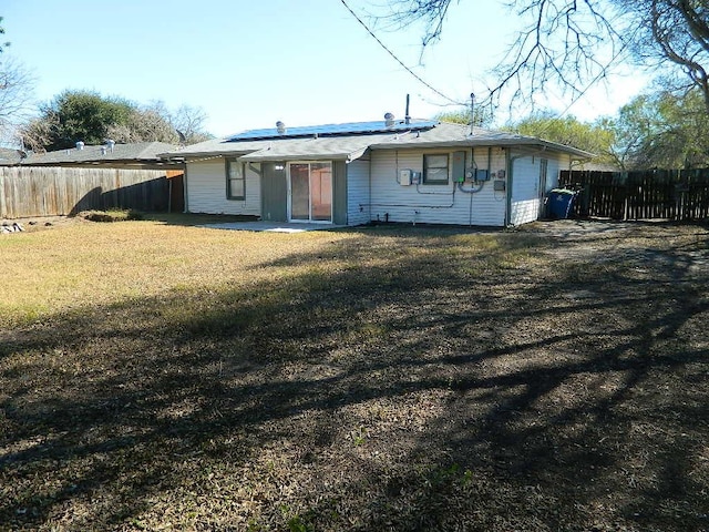 back of property featuring a lawn, solar panels, and a patio