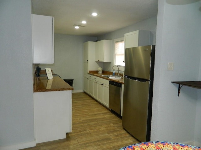 kitchen featuring sink, white cabinetry, light hardwood / wood-style floors, and appliances with stainless steel finishes