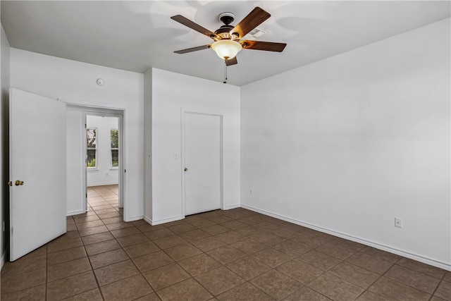 unfurnished bedroom featuring dark tile patterned flooring, ceiling fan, and a closet