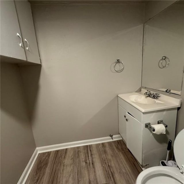 bathroom featuring vanity, wood finished floors, toilet, and baseboards