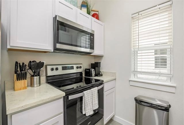 kitchen with light stone counters, white cabinetry, and stainless steel appliances