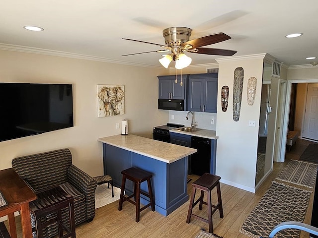 kitchen featuring blue cabinetry, a kitchen bar, sink, kitchen peninsula, and black appliances