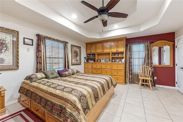 tiled bedroom with ceiling fan and a tray ceiling