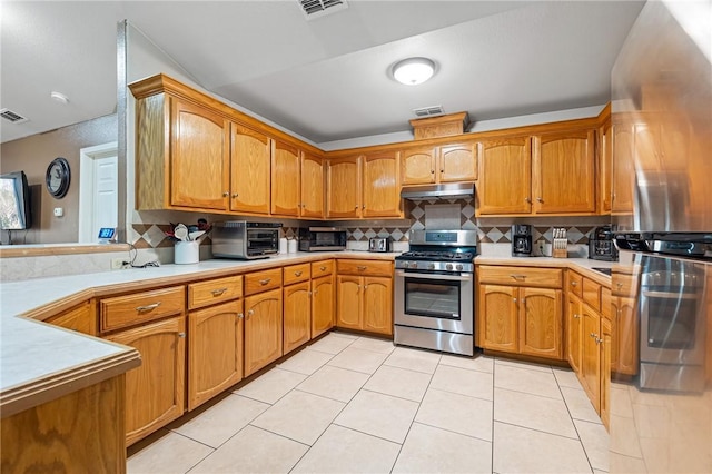 kitchen featuring decorative backsplash, appliances with stainless steel finishes, and light tile patterned floors