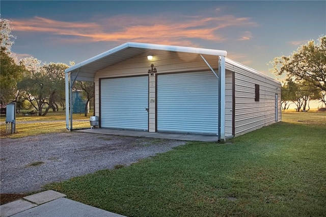 garage at dusk featuring a yard