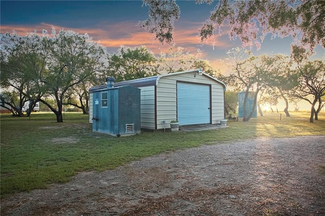 outdoor structure at dusk featuring a lawn and a garage