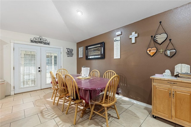 tiled dining space featuring vaulted ceiling and french doors