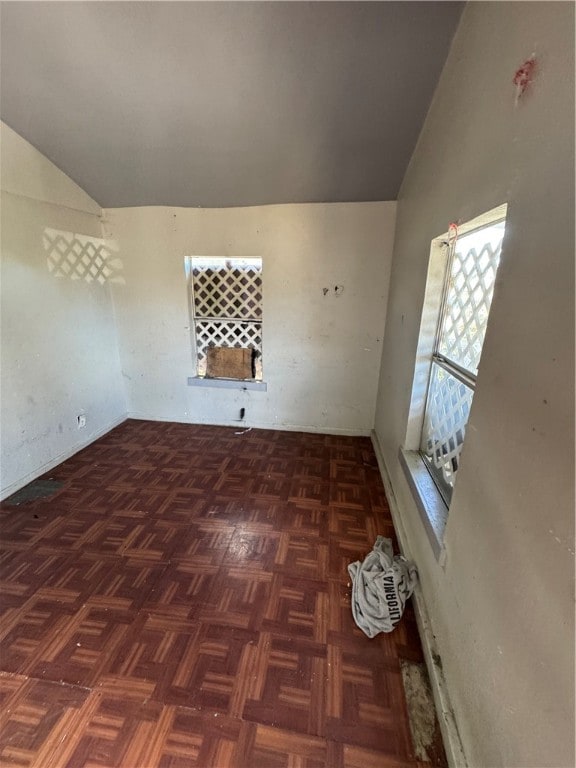 unfurnished room with lofted ceiling and dark parquet flooring