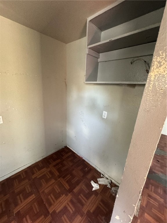 clothes washing area with dark parquet flooring