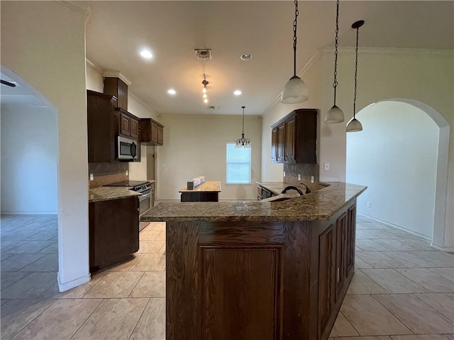 kitchen featuring dark brown cabinets, dark stone countertops, decorative light fixtures, and appliances with stainless steel finishes