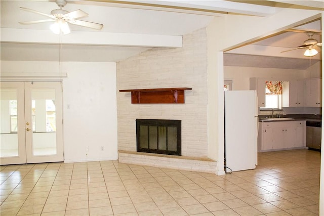 33 Encino Loma, Beeville, TX 78102 - unfurnished living room with a ceiling fan, light tile patterned floors, french doors, and a brick fireplace
