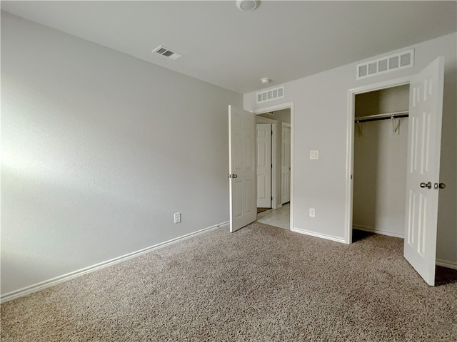 unfurnished bedroom with light colored carpet and a closet