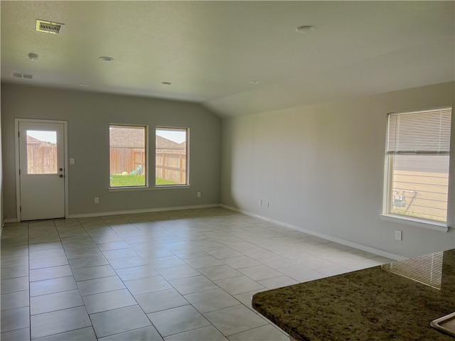 spare room featuring a wealth of natural light, light tile patterned floors, and vaulted ceiling