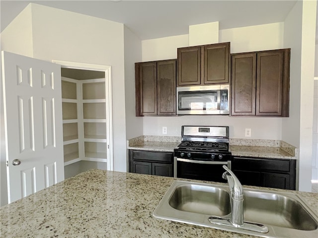 kitchen featuring light stone countertops, appliances with stainless steel finishes, sink, and dark brown cabinets