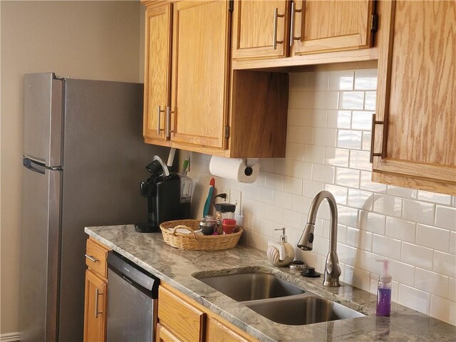 kitchen featuring dishwasher, decorative backsplash, light stone counters, and a sink