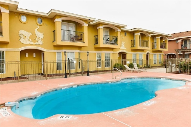 community pool with a patio and fence