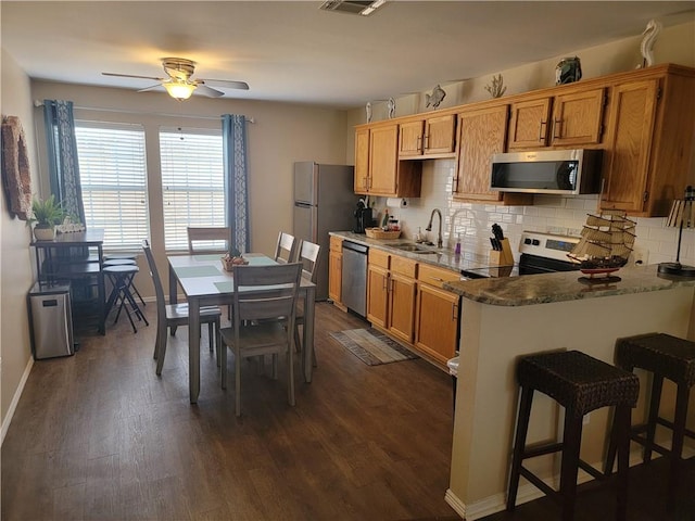 kitchen with decorative backsplash, dark wood-style floors, appliances with stainless steel finishes, and a sink