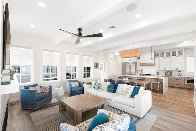 living room with light wood-type flooring, ceiling fan, and beamed ceiling