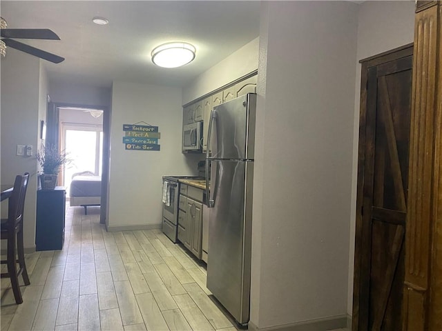 kitchen with gray cabinets, ceiling fan, stainless steel appliances, and light wood-type flooring