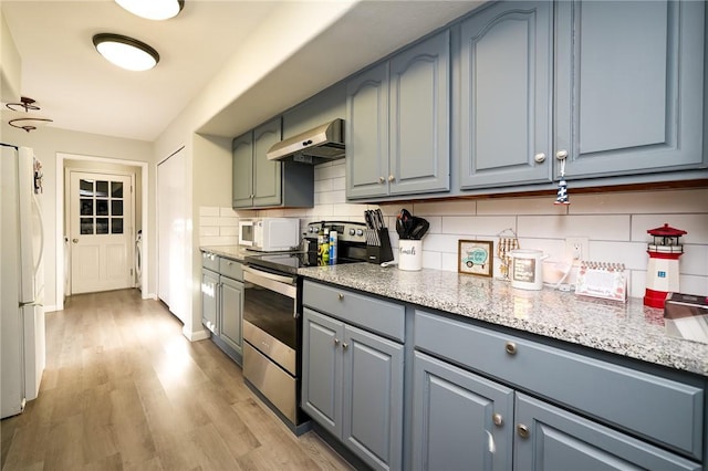 kitchen with backsplash, light stone counters, white appliances, extractor fan, and light hardwood / wood-style flooring