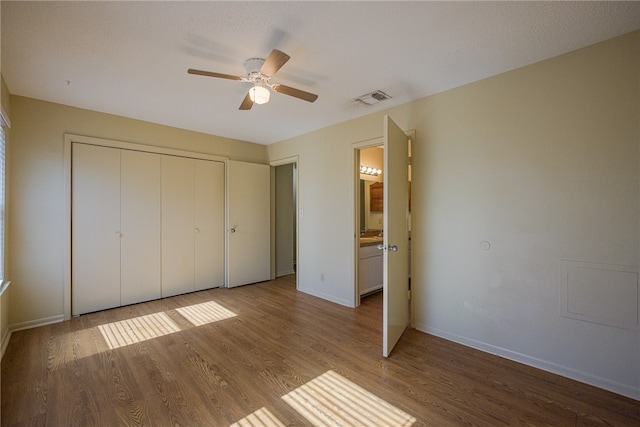 unfurnished bedroom featuring a textured ceiling, a closet, hardwood / wood-style flooring, and ceiling fan