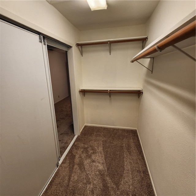 walk in closet featuring dark carpet