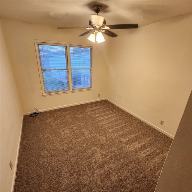 spare room featuring dark carpet, a ceiling fan, and baseboards