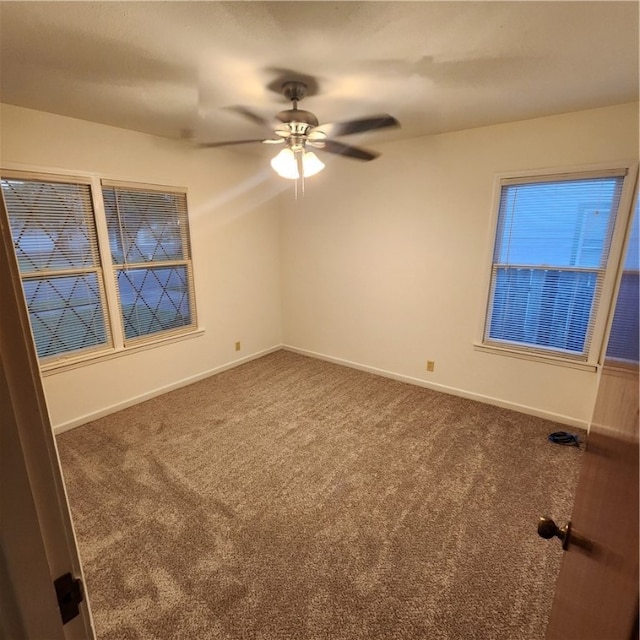 unfurnished room featuring dark colored carpet, ceiling fan, and baseboards