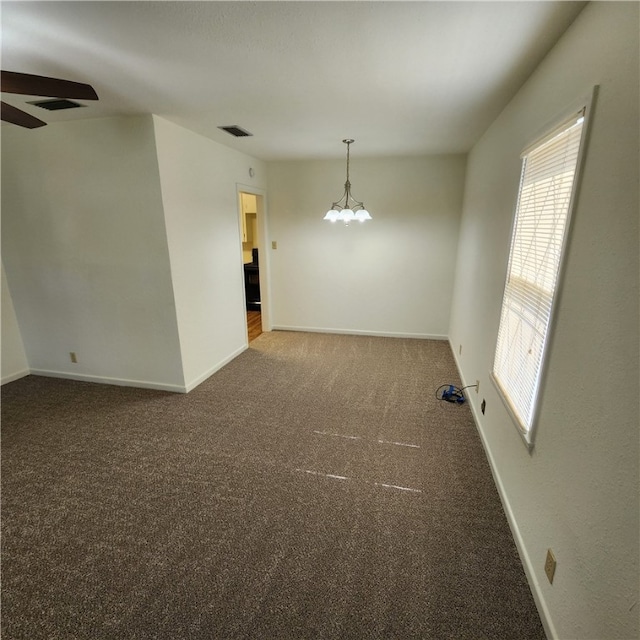 carpeted spare room with a chandelier, visible vents, and baseboards