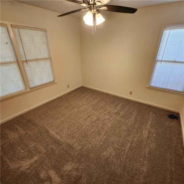 empty room with ceiling fan, dark colored carpet, and baseboards