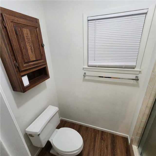 bathroom with toilet, baseboards, and wood finished floors