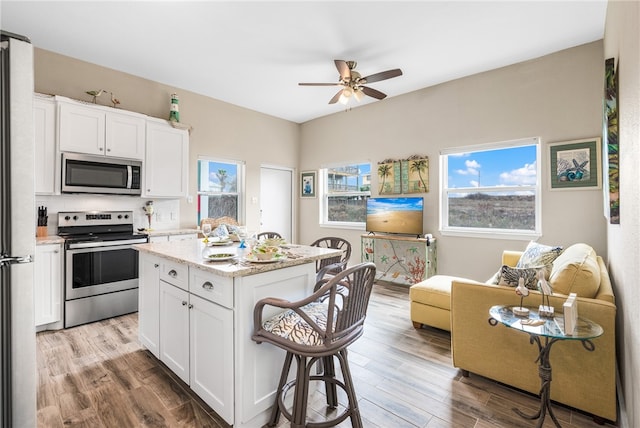 kitchen with white cabinets, light wood-type flooring, stainless steel appliances, and a kitchen island